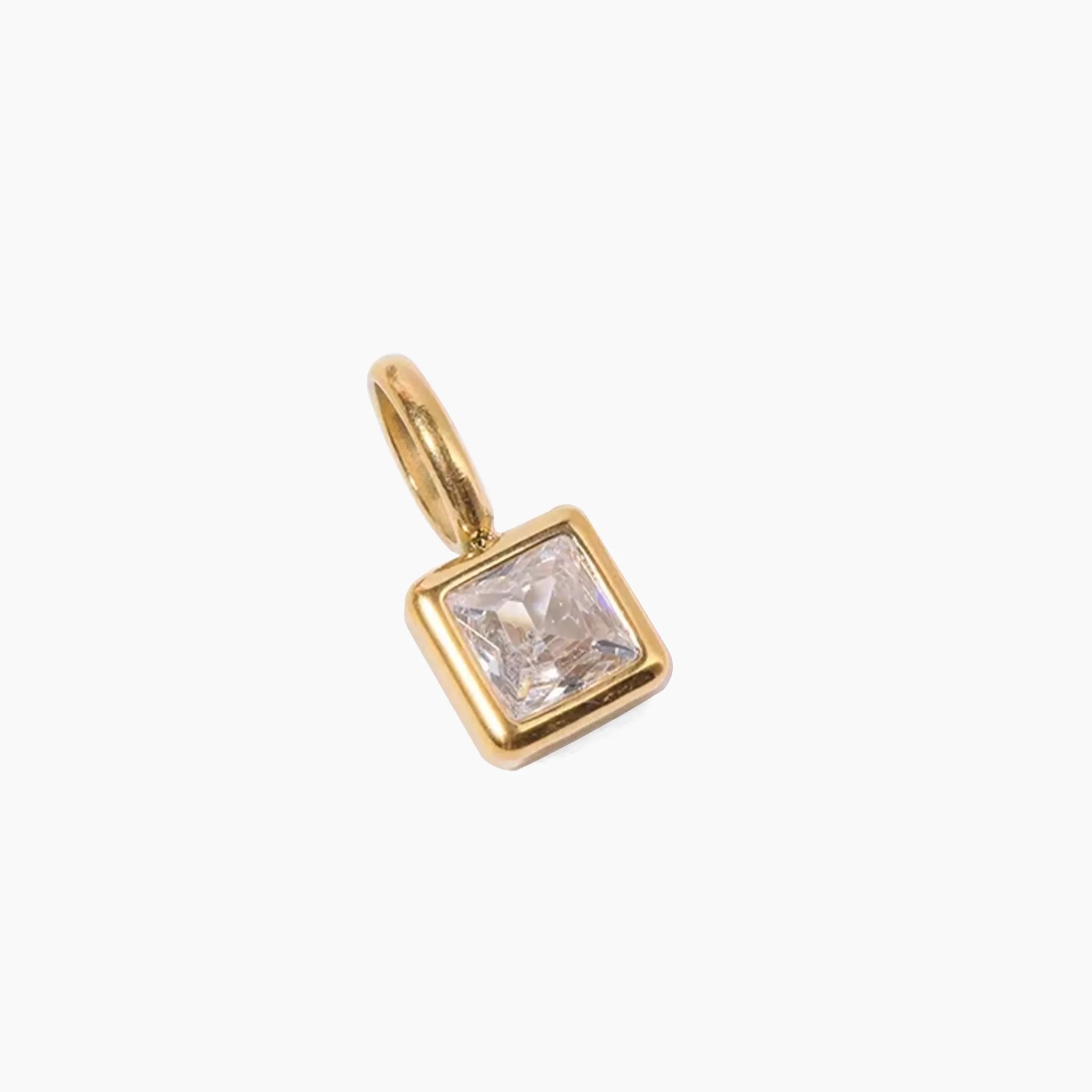 April birthstone charm, golden pendant with a clear gemstone on a white background
