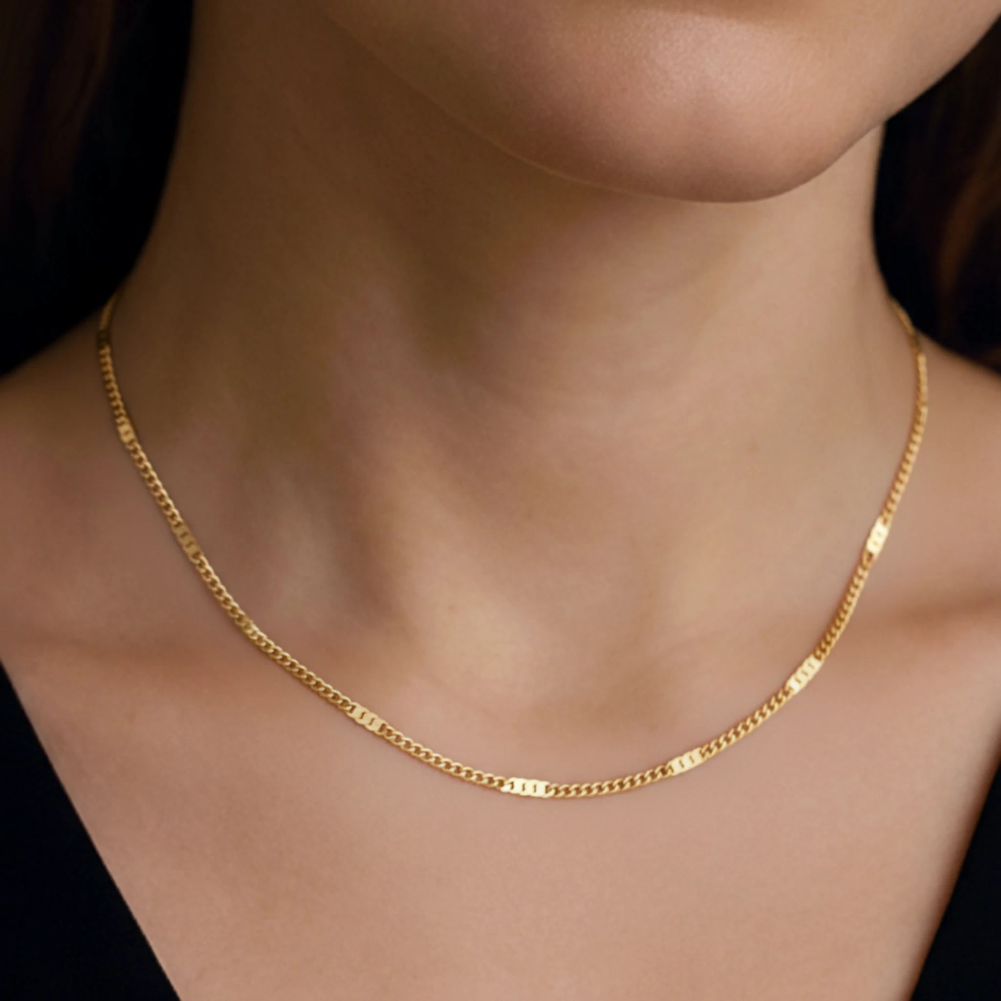 Dainty chain necklace on a person wearing a black top