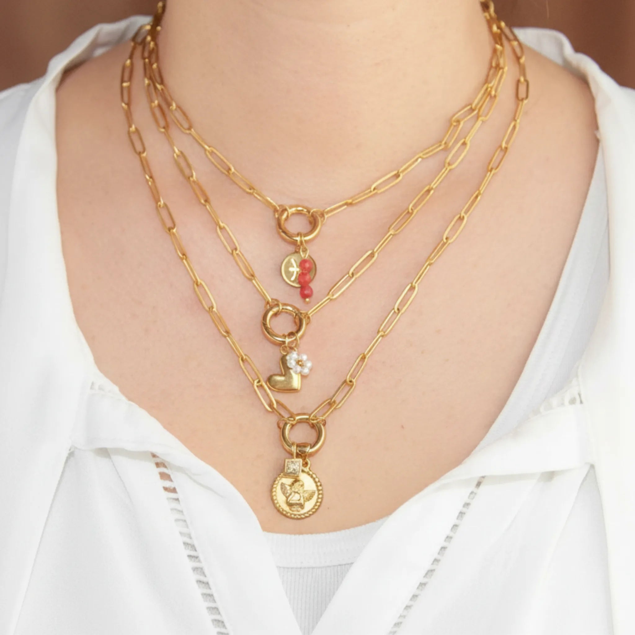 Chain necklaces with various charms on a person wearing a white shirt