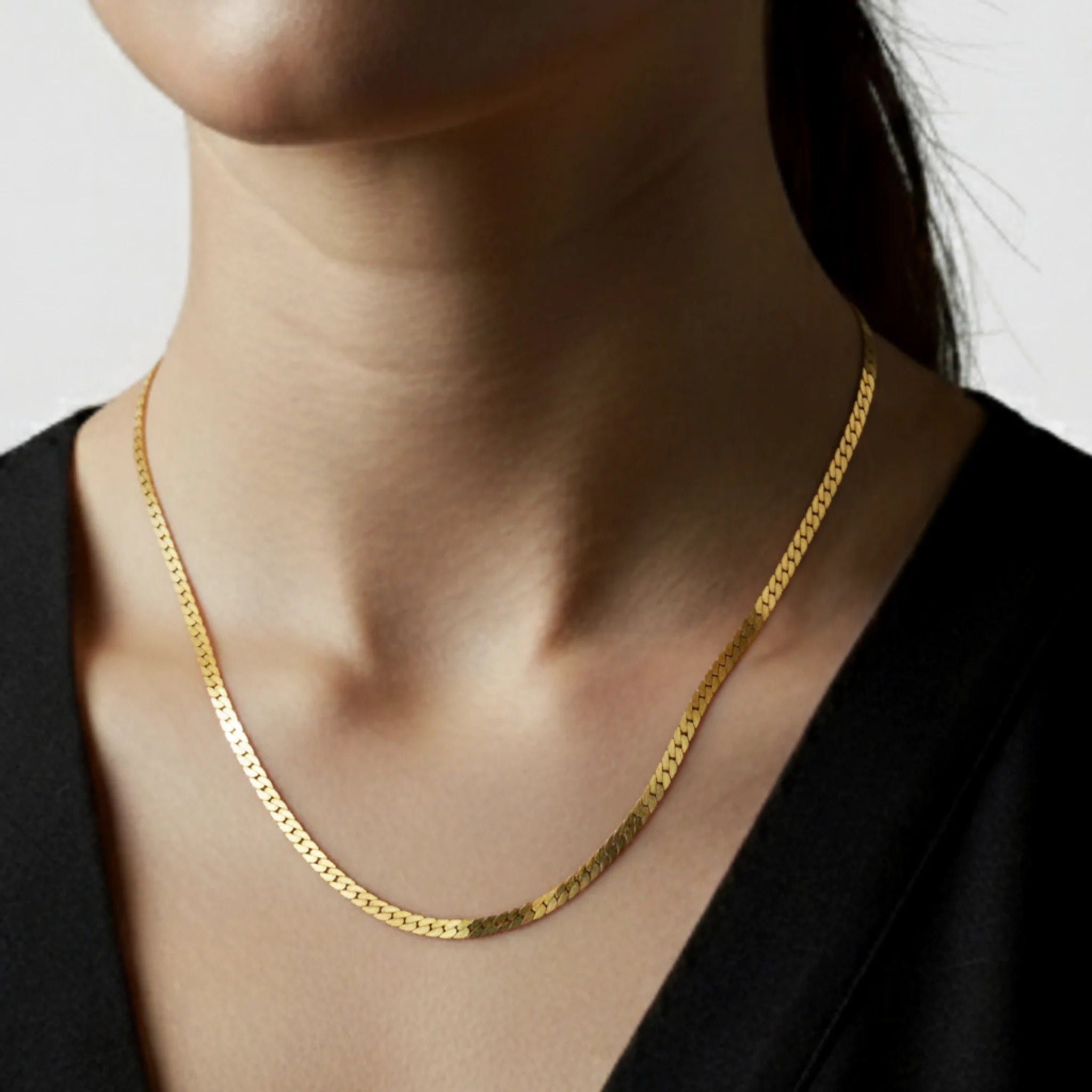 Flat chain long necklace on a person wearing a black top