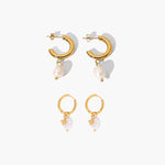 Pair of golden hoop earrings with pearl-like charms on a white background