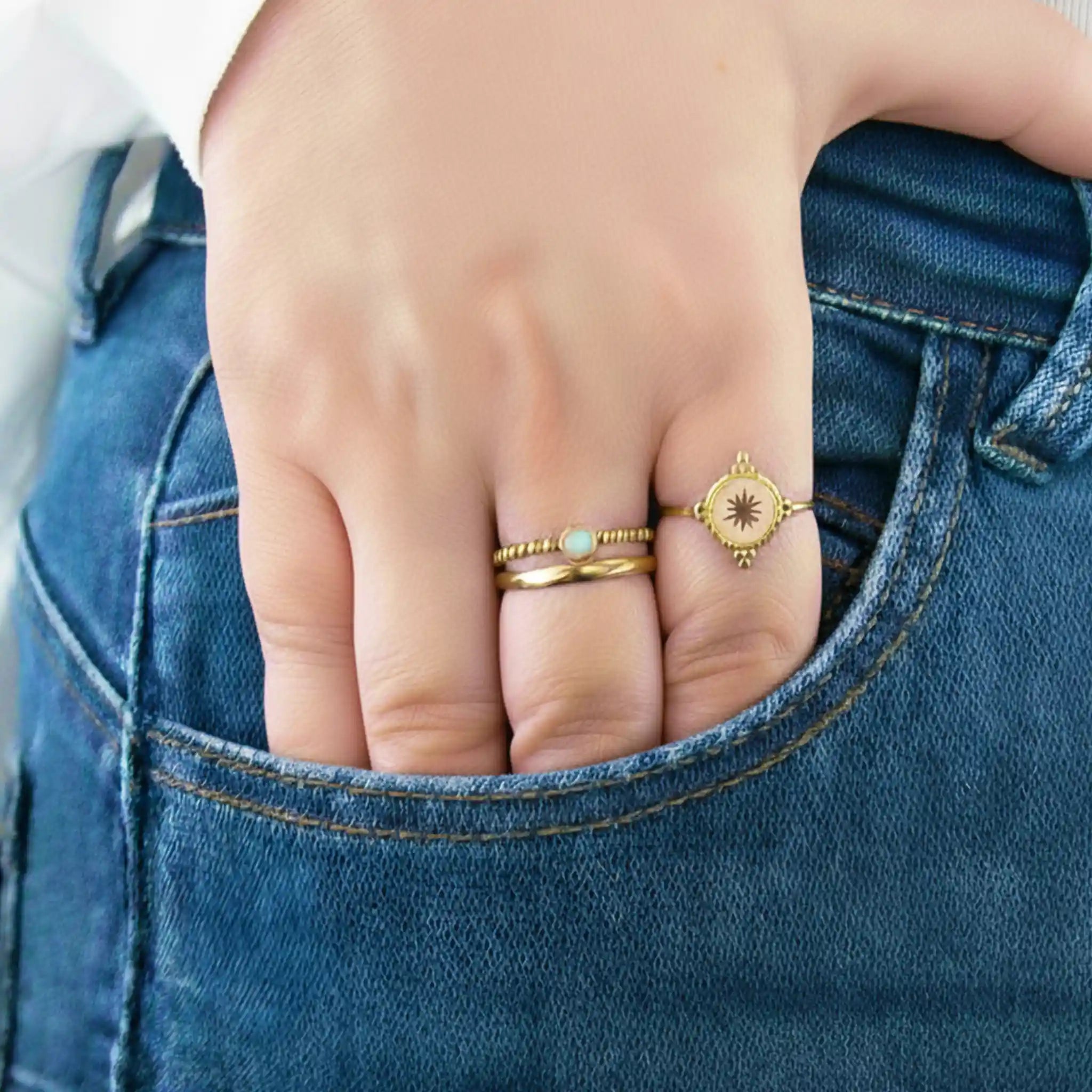 Hand with gold rings on a blue denim background