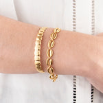 Golden shells set on a person's wrist with a white background