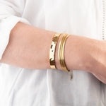 Golden bracelets on a person's wrist against a white background
