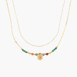 Golden necklace with colorful beads and a sun charm on a white background
