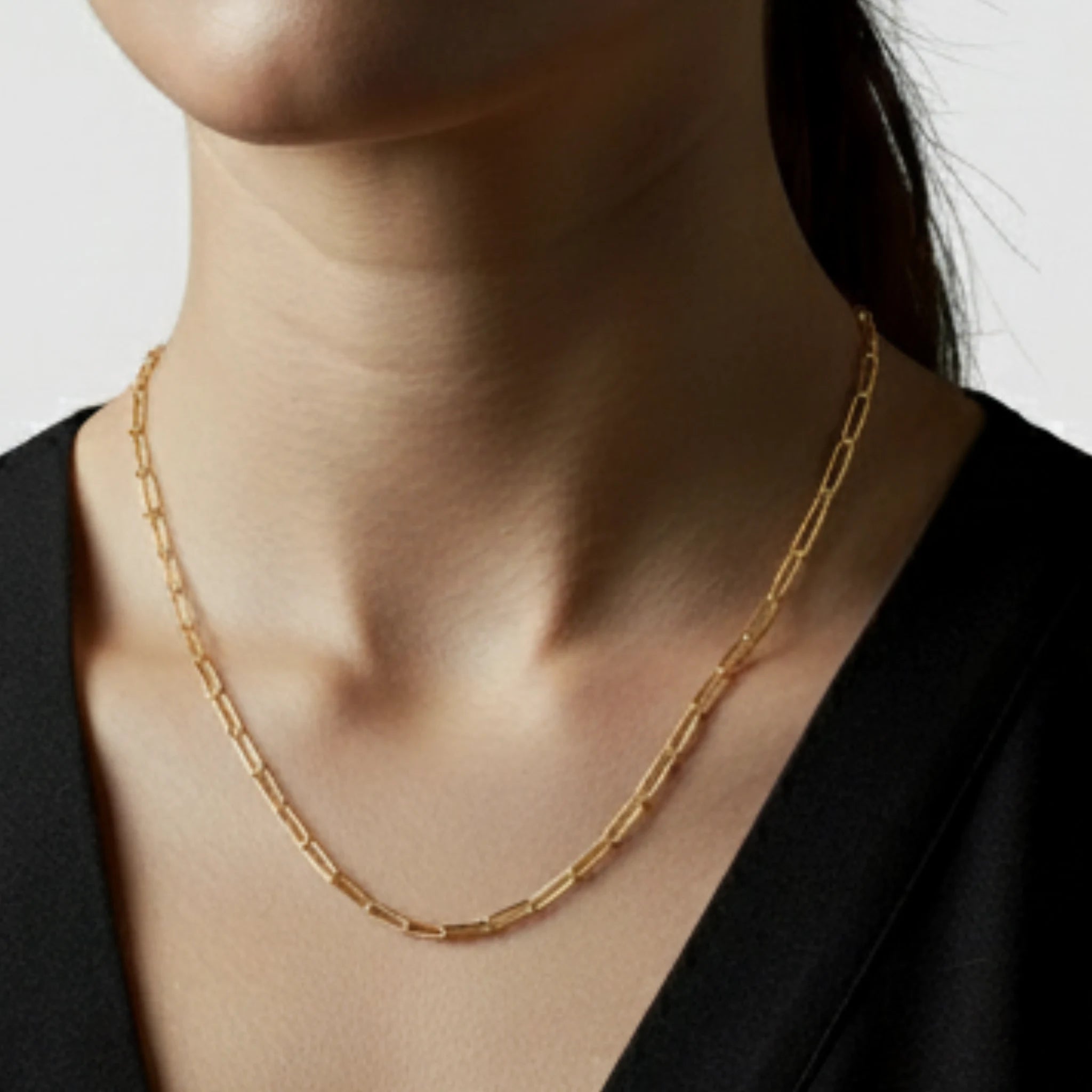 Paperclip chain long necklace worn by a person on a white background