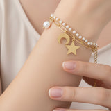 Gold bracelet with star and moon charm on a wrist against a neutral background
