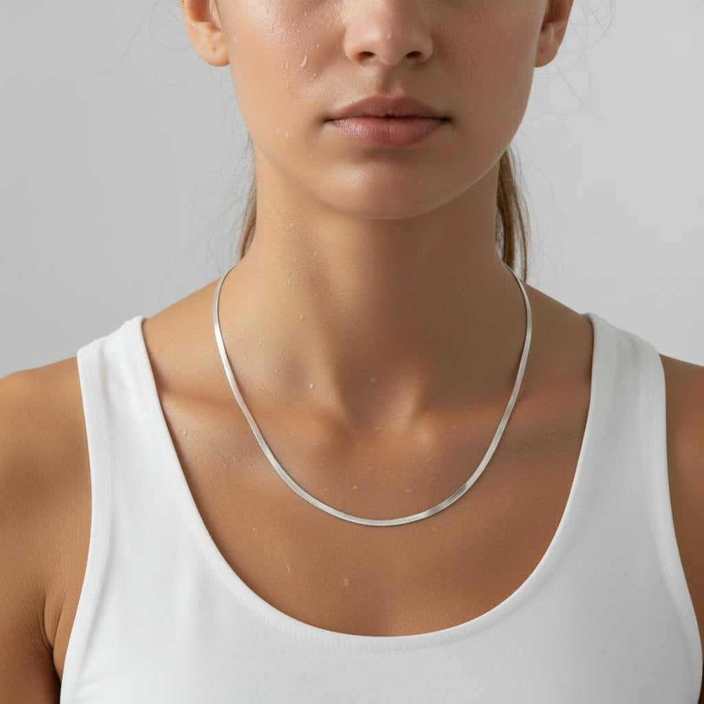 a woman wearing a silver herringbone necklace and a white top