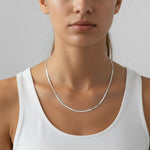 a woman wearing a silver herringbone necklace and a white top