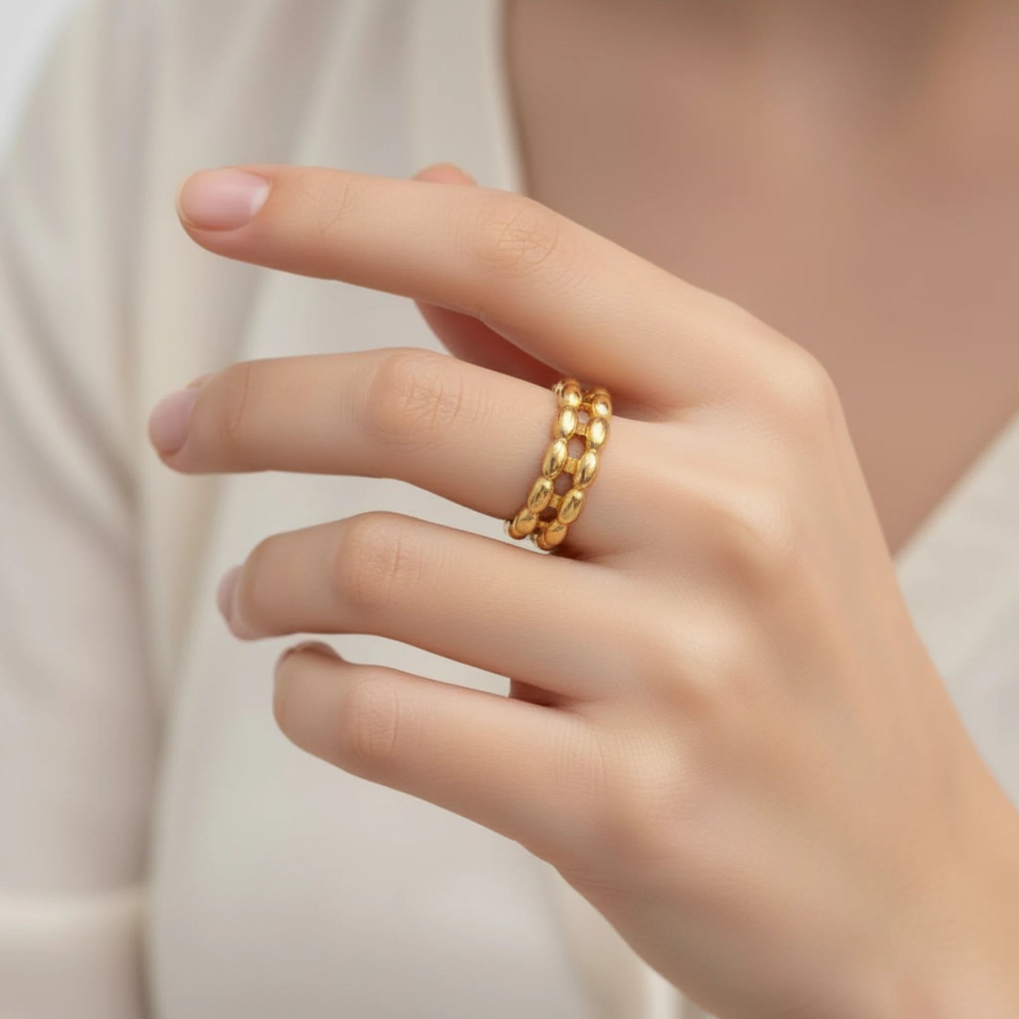 Gold double band bead ring on a woman's finger against a neutral background