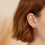 Close-up of an ear wearing a gold ball earring
