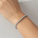 Silver beaded bracelet on a wrist against a neutral background