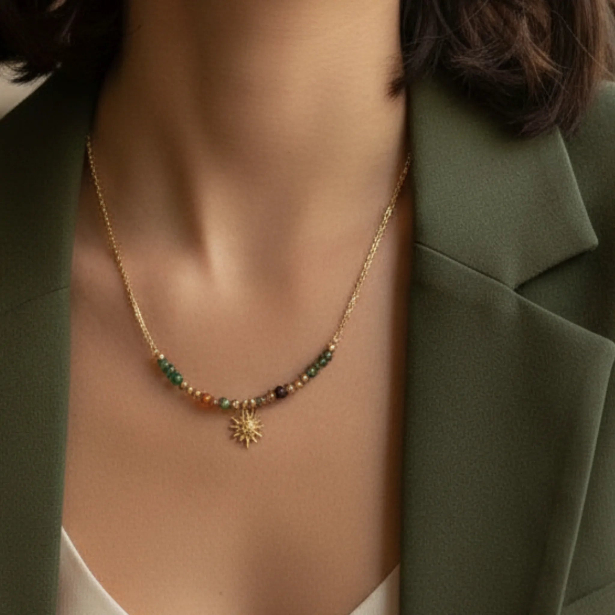 Necklace with a sunflower pendant worn by a person in a green blazer.