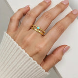 Hand wearing a gold ring with a turquoise stone on a white background